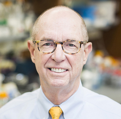 Headshot of Larry Marnett wearing tortoise-shell eyeglasses, a blue shirt, and a yellow tie.