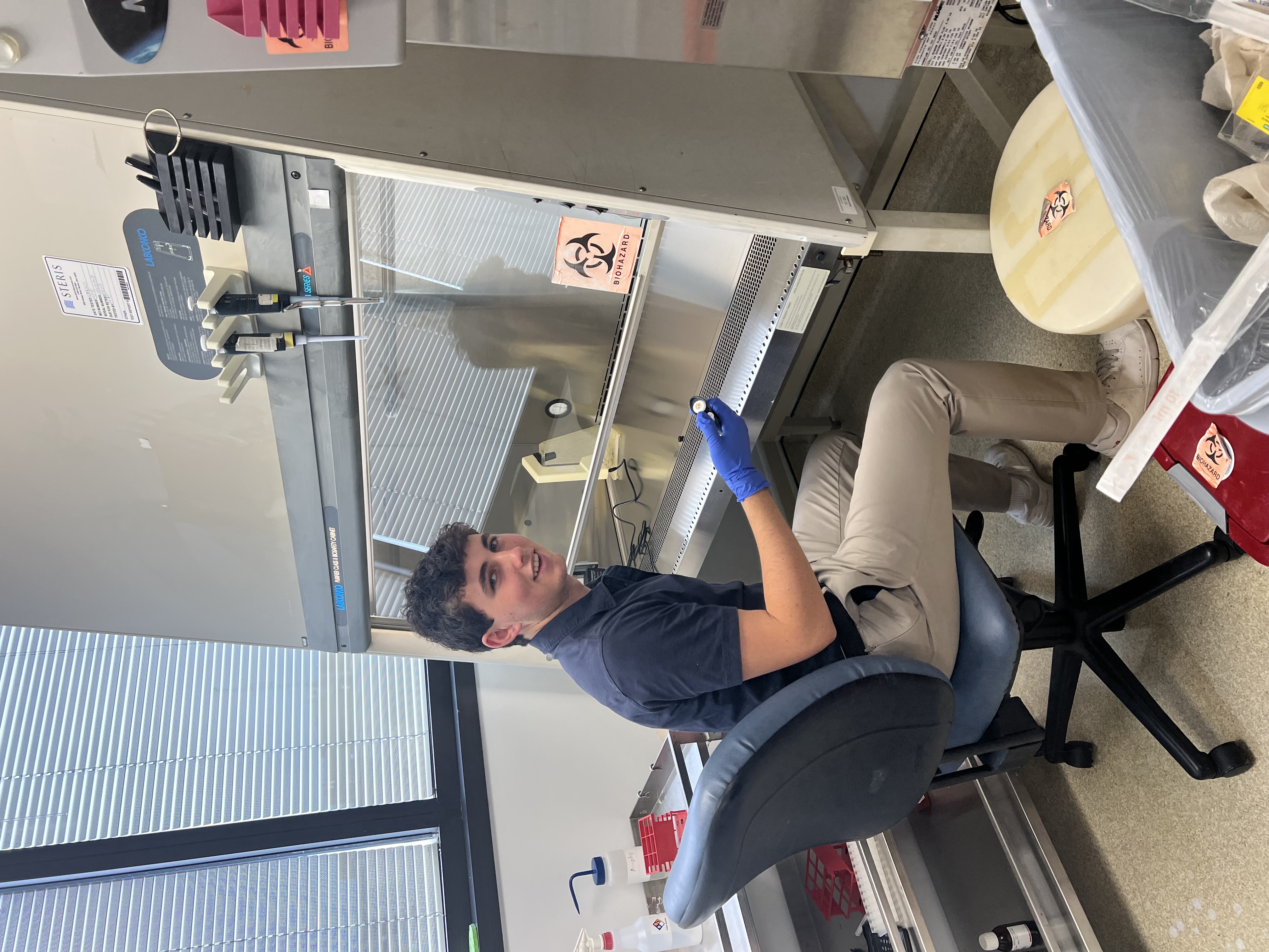 Benjamin Gordon wearing nitrile gloves and working in a cell culture hood.