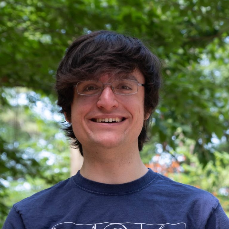 Headshot of Kesler with tree foliage in the background.