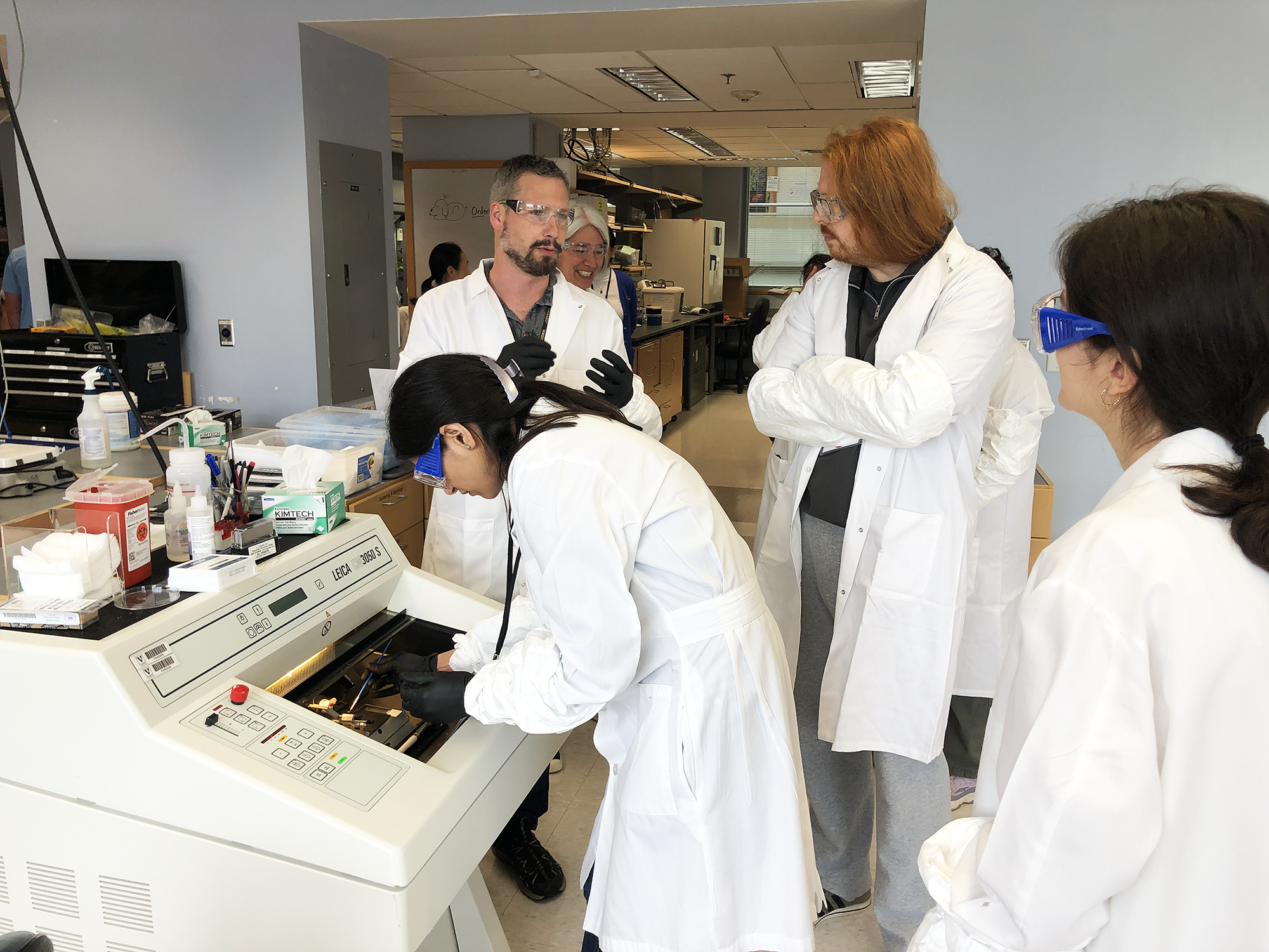 Scientists in lab coats working at an instrument.