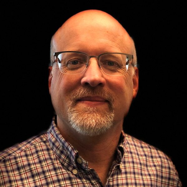 Headshot of Kevin Schey on a flat black background.