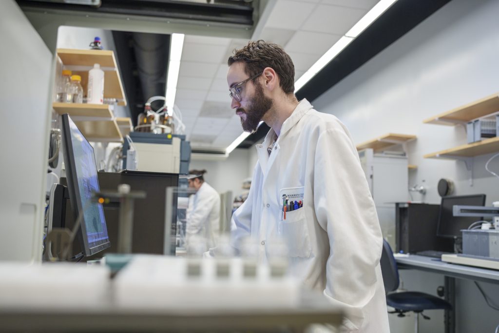 Photo of lab technician looking at a computer monitor.
