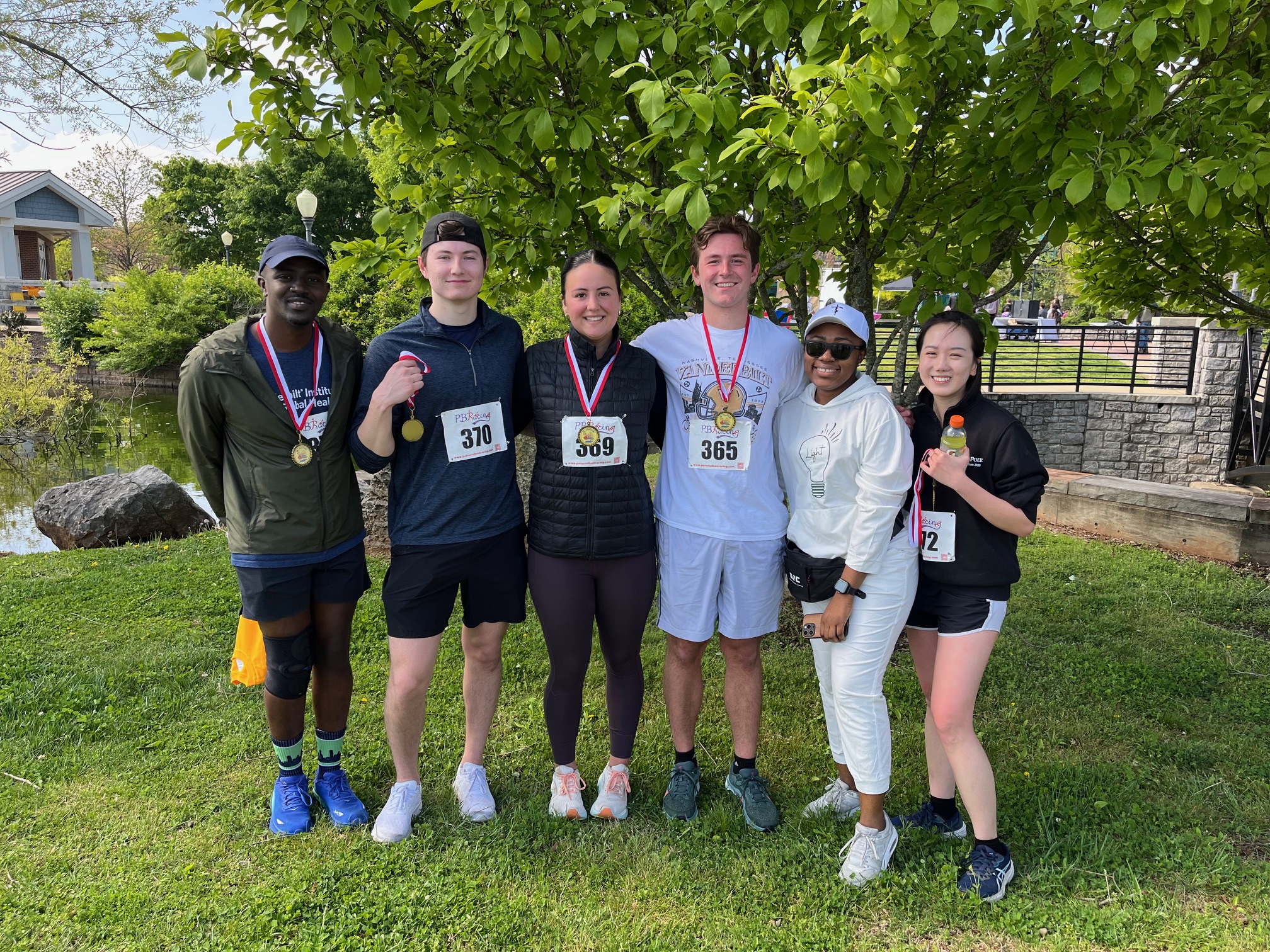 Six students wearing gold medals smile and pose together.
