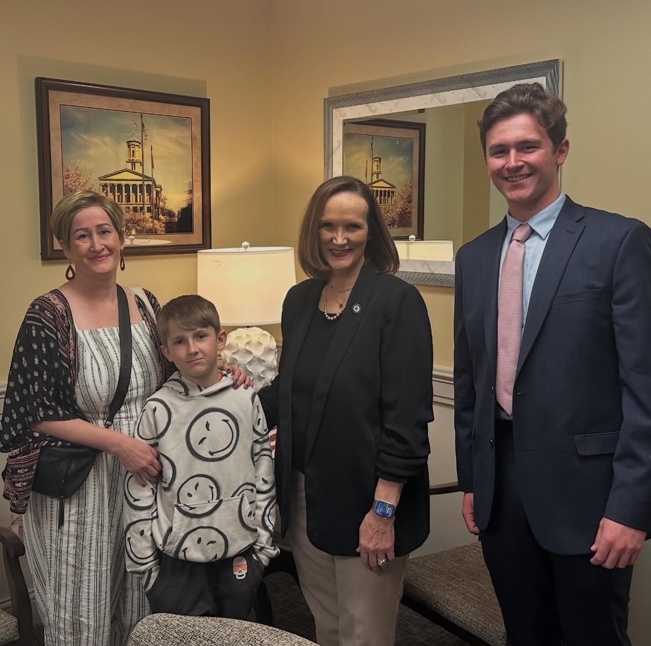 Two individuals and a child smile and pose with a legislator.
