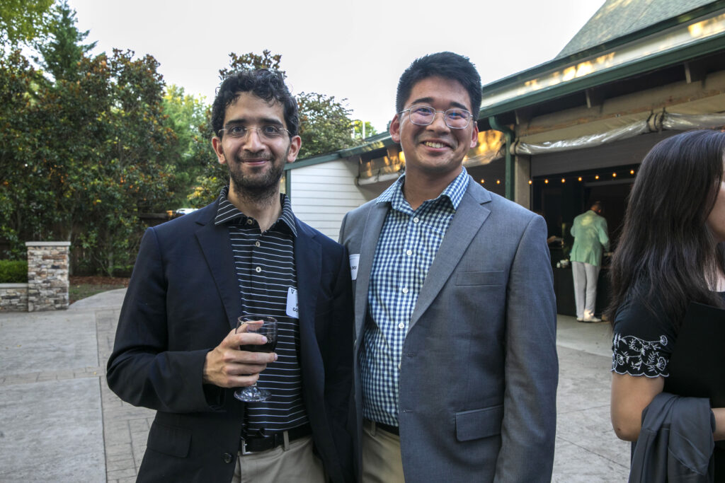 Two men in business casual clothing stand outside at a picnic