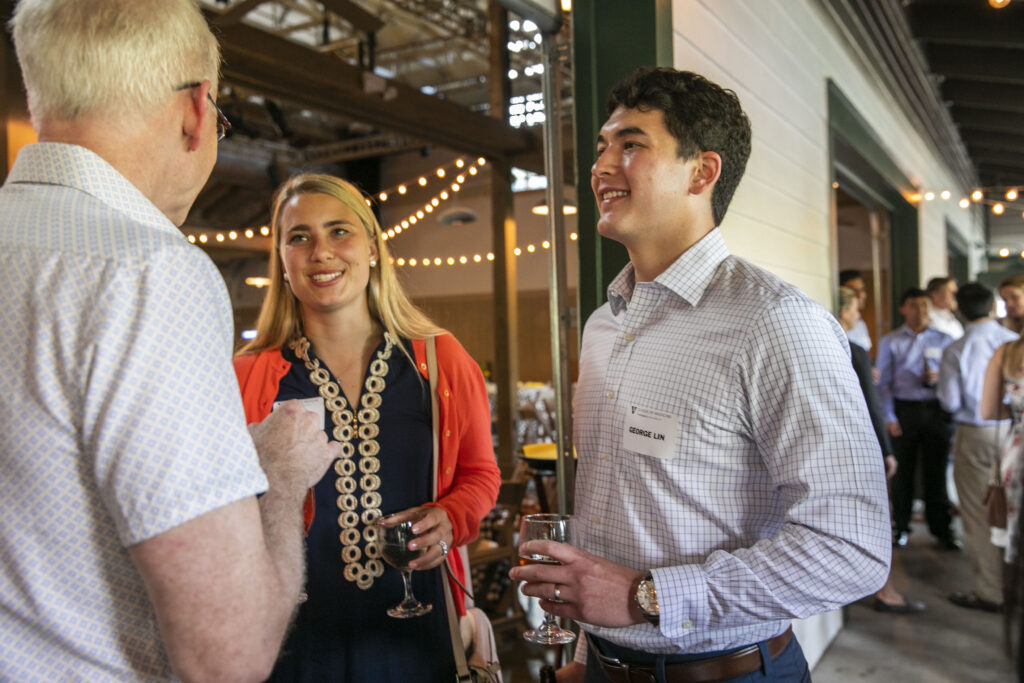 A couple speaks to a dean at a medical school picnic