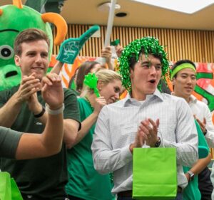 Students in green clothing and spirit wear yell and clap