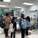 A medical student volunteer demonstrates a simulation for high school students