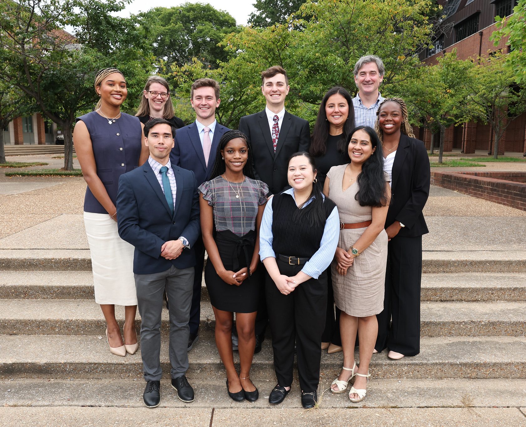 New students and their professors pose together on steps.