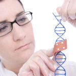 A female researcher wearing a lab coat applies a bandaid to a DNA double-helix model.