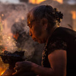 Woman lighting copal incense at the cemetery during the "Alumbrada" vigil in San Andrés Mixquic
