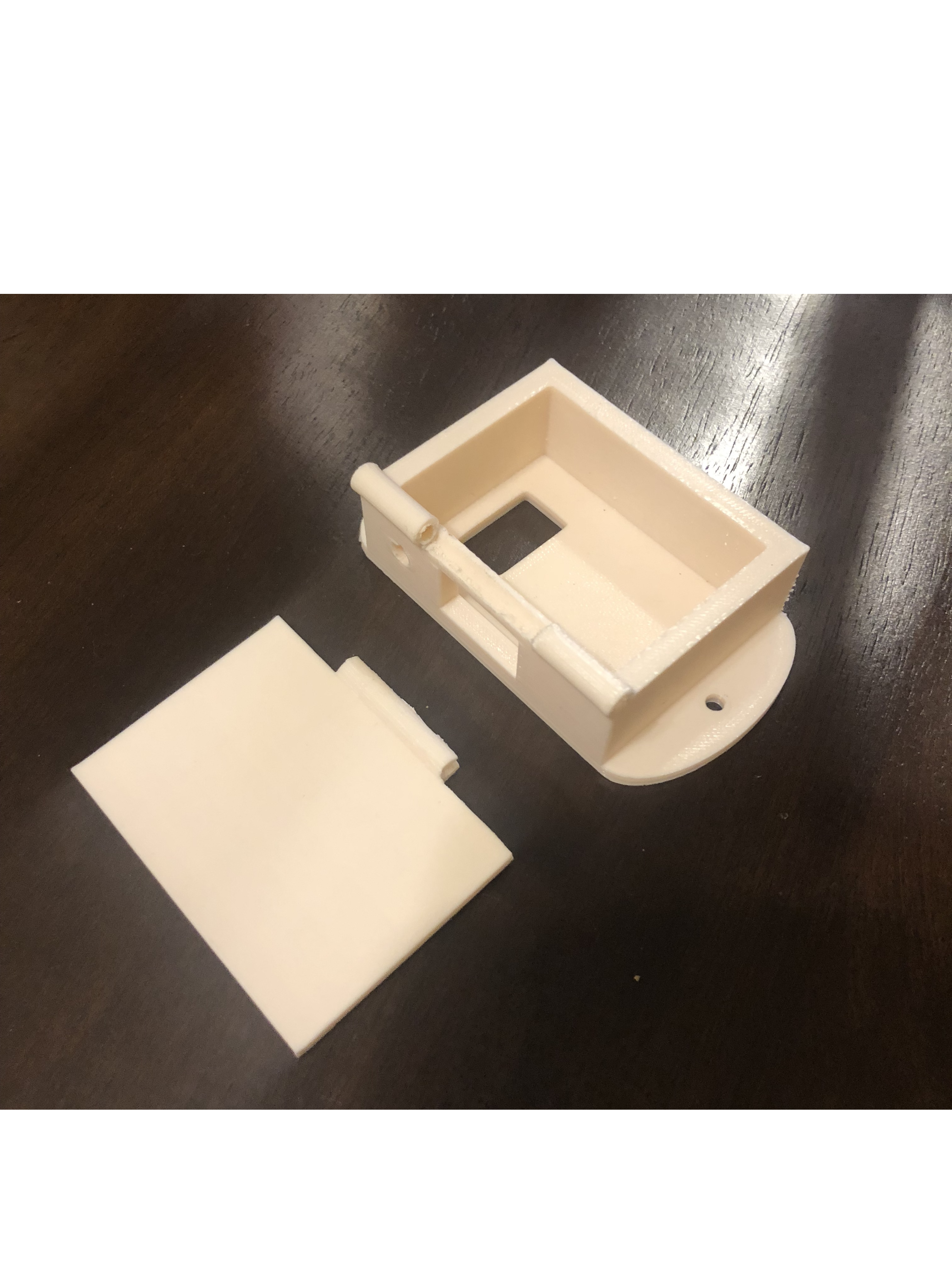 3D-printed battery casing. This casing contains two holes in what will be the top side, one rectangular, one circular, that will accommodate the on/off switch and the battery indicator LED respectively. The hole in the back will allow wires to be fed from the battery, LED, and switch to the rest of the circuit housed inside the headset.
