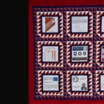 red quilt with book covers, papers, and graphs in the quilt squares