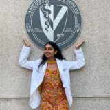 A medical student poses beneath the school seal