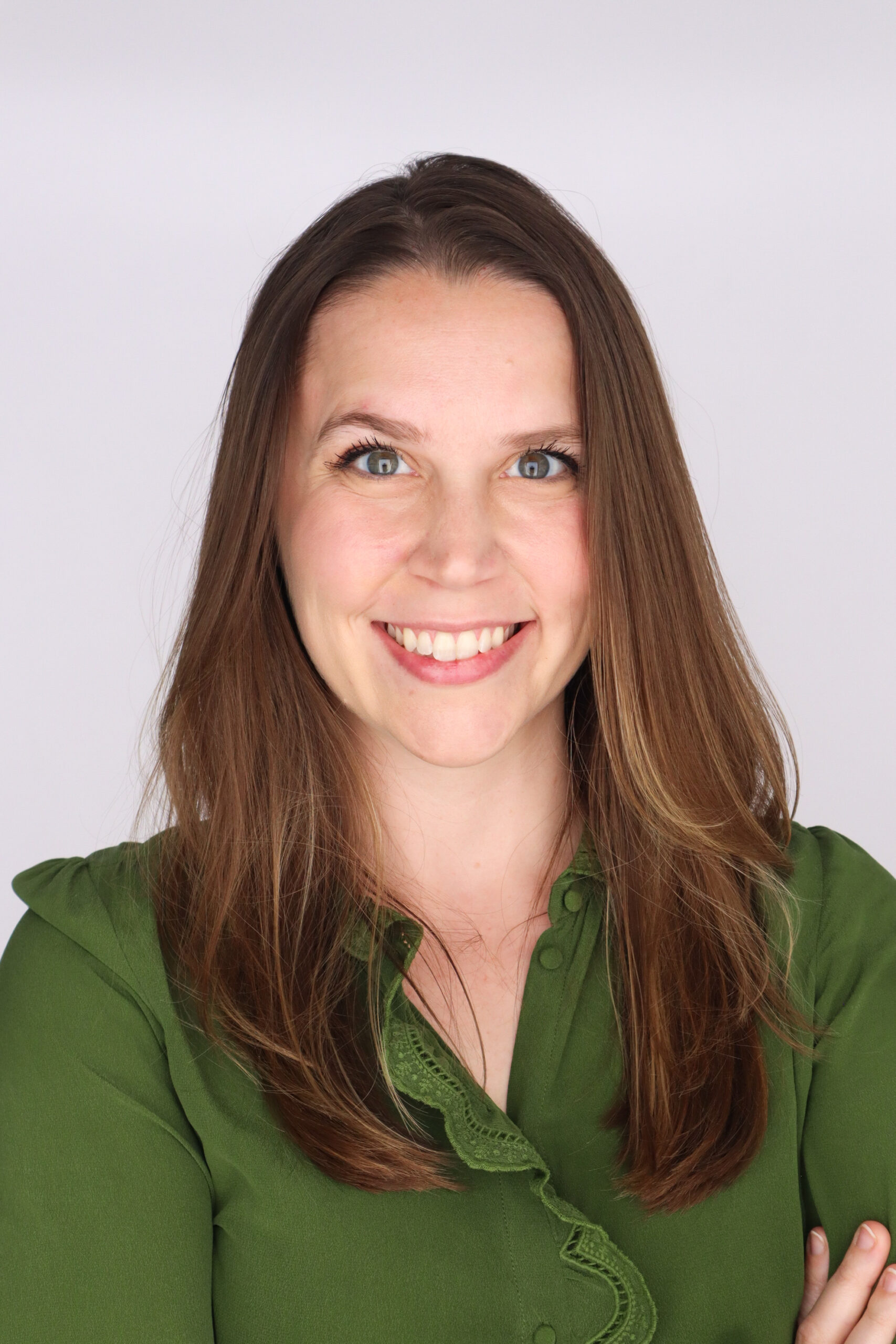 Headshot photo of a woman with brown hair and a green shirt