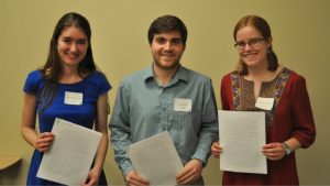 Three students pose with their writing pieces after share their work with the Undergraduate Writing Symposium audience.