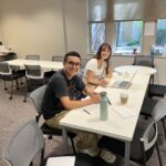 This image depicts a Writing Studio writing consultation between a male-presenting student and a female-presenting student in the Writing Studio's space.