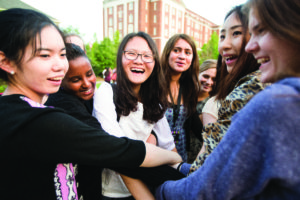 A group of female international students are huddled together doing an icebreaker outside on Move-In Day