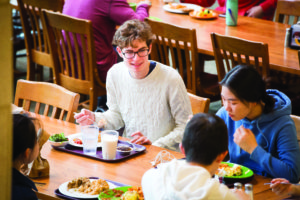 Students gathered at a dining hall table having conversation over a meal