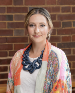Headshot of Emma Reiners. Subject is wearing a multi-color shawl and professional dress.