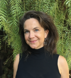 Headshot of Madeleine Casad wearing black, professional dress and standing in front of a tree.