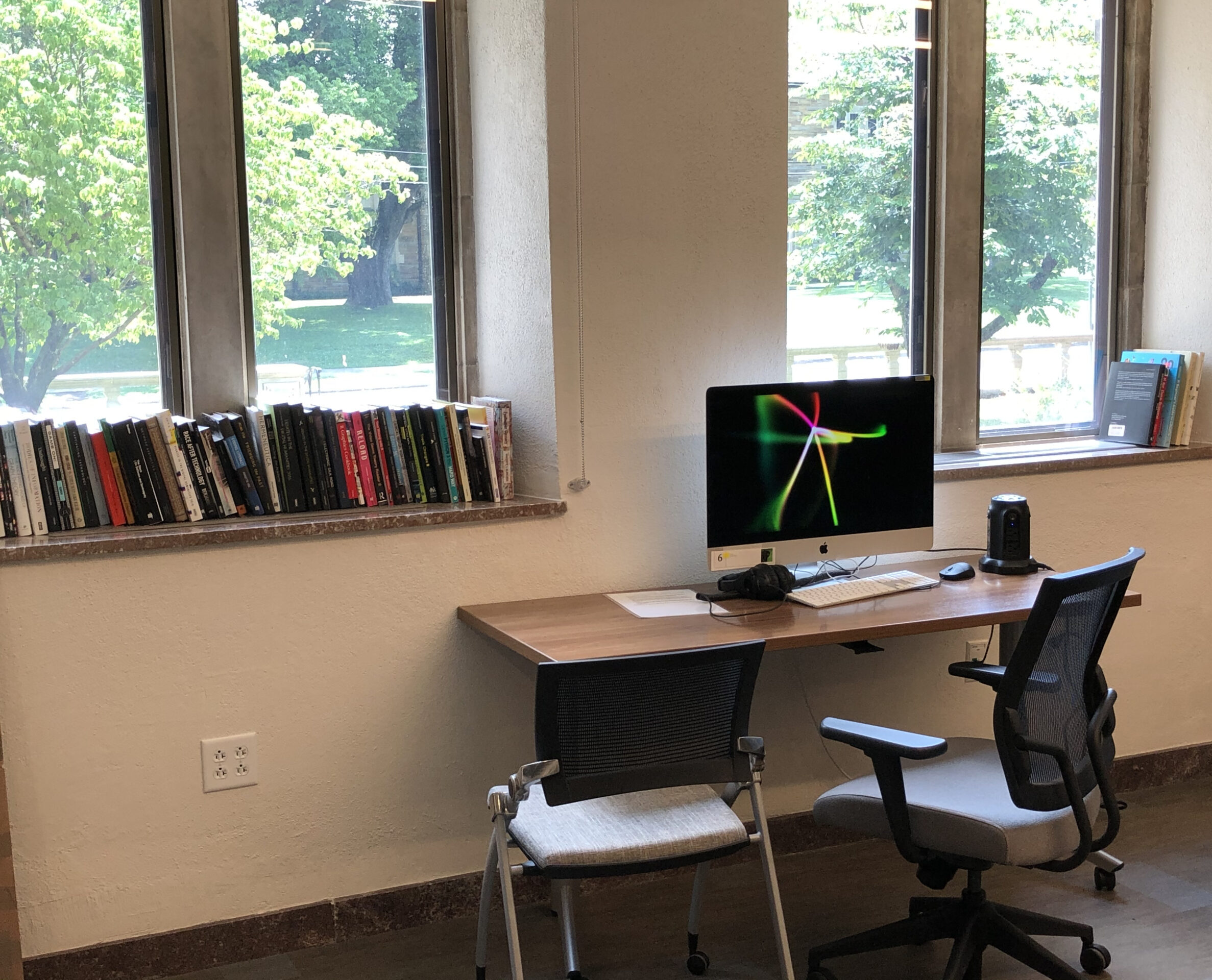 computer with two chairs and books on a window sill