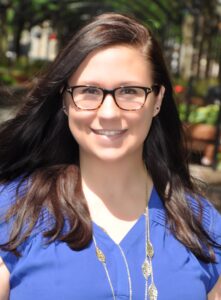 person in blue top with glasses smiling