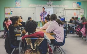 teacher at the head of a classroom teaching young students