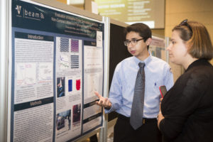 A student points out text on his poster to an attendee at the Undergraduate Research Fair.