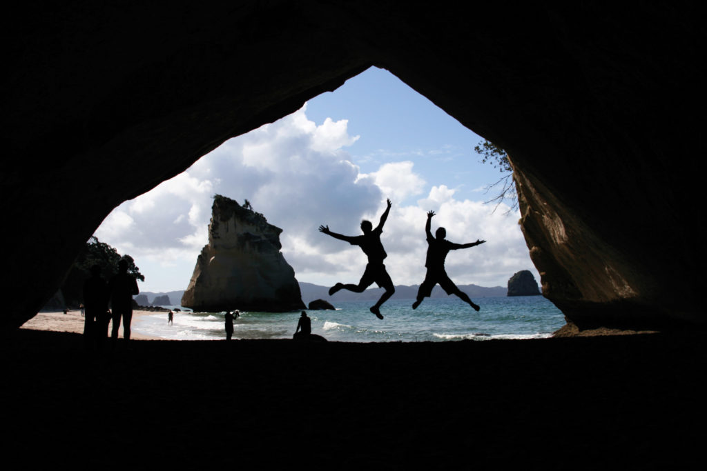 Students jumping in cave tunnel while abroad