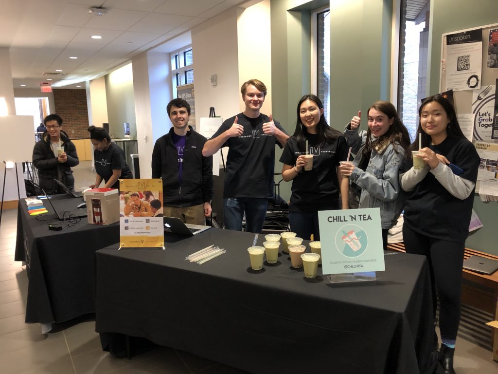 Photo of students standing behind an information table giving thumbs up with bubble tea