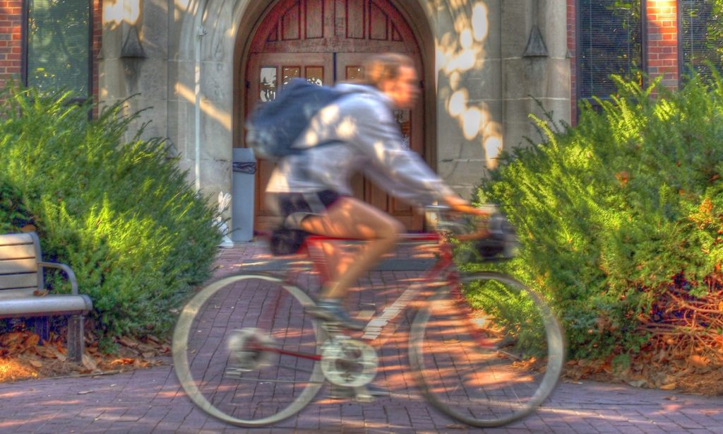 Person riding a bike past a building on campus
