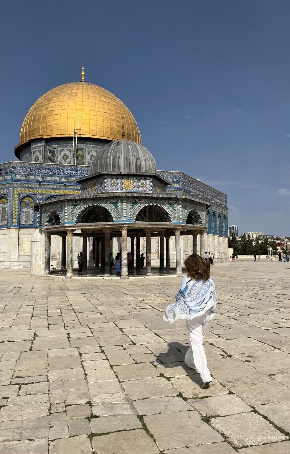 Woman with flowing shirt walking toward the Dome of the Rock in Jerusalem