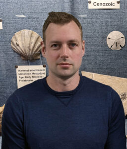 Man smiling in front of fossil display