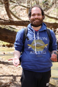 Man in blue sweatshirt smiling holding fossils