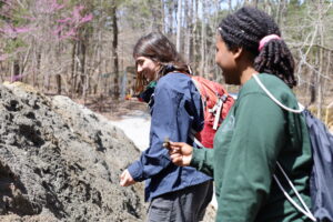 Two women smile while looking at fossils