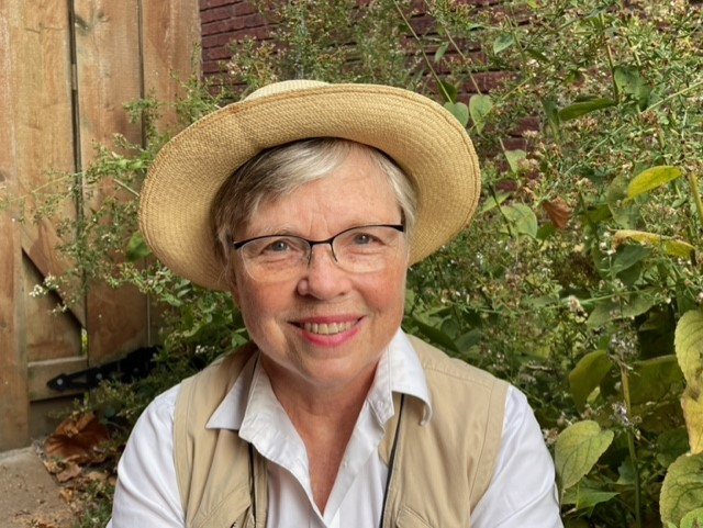 Joan smiling in a hat outside