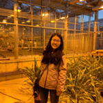 Assistant Professor Lin Meng in the greenhouse smiling. Sepia tone from low light at night.