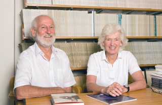 Peter and Rosemary wearing white in front of a bookshelf full of books