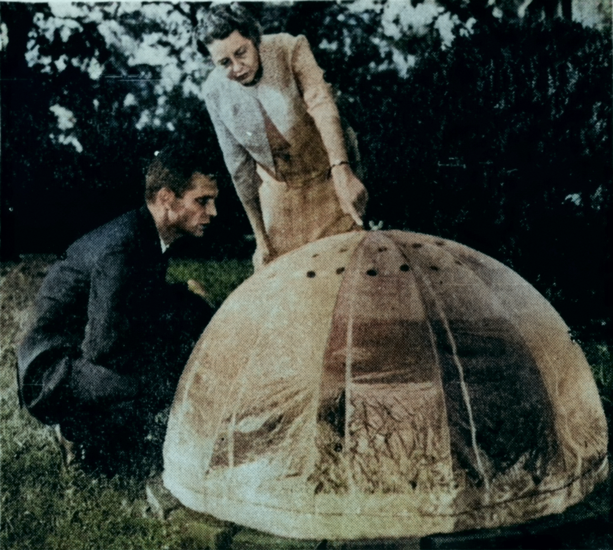 A colorized photo of Ben Channell leaning over and Elsie Quarterman pointing at a plant in a plastic bubble.