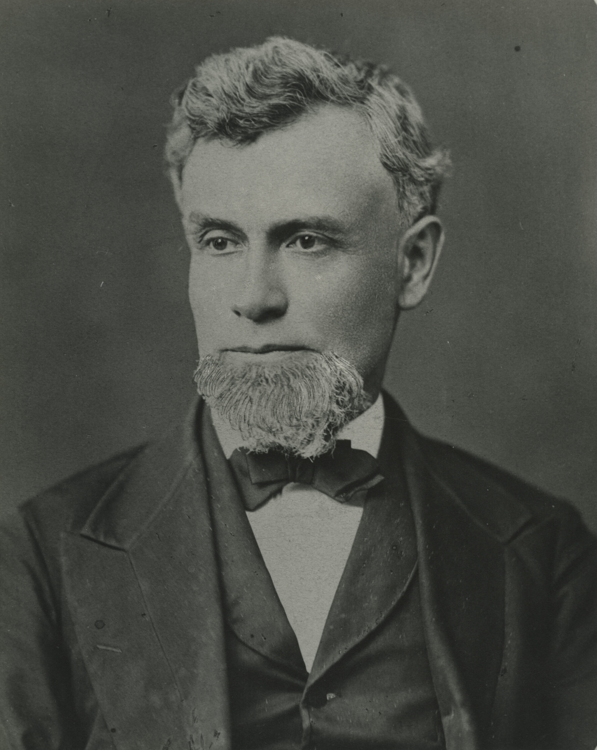 James Safford portrait, black and white. Safford is wearing a black suit and bowtie looking to his right.