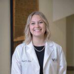 Abby in a white lab coat smiling