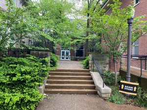 This photograph features a set of steps in the foreground leading into a courtyard at the far end of which are the glass double doors into the Curb Center building, the easiest point of access to Tutoring Services' location.