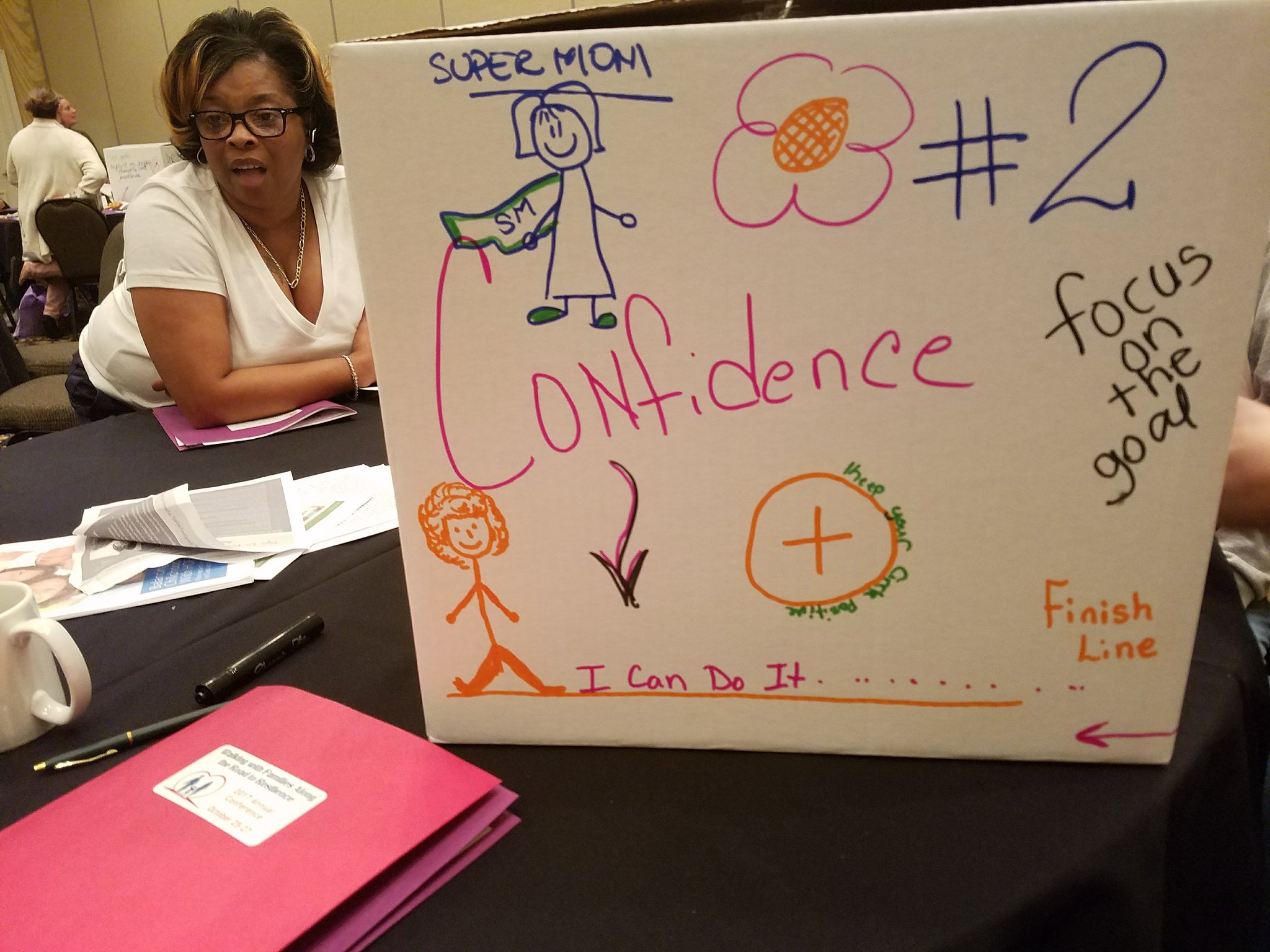 A woman in front of a board with encouraging phrases for mothers