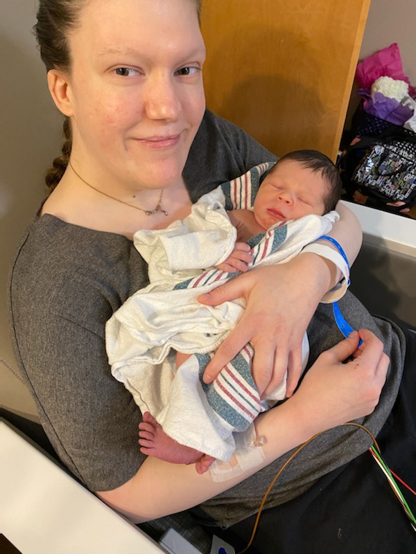 Woman with dark braided hair holding an infant