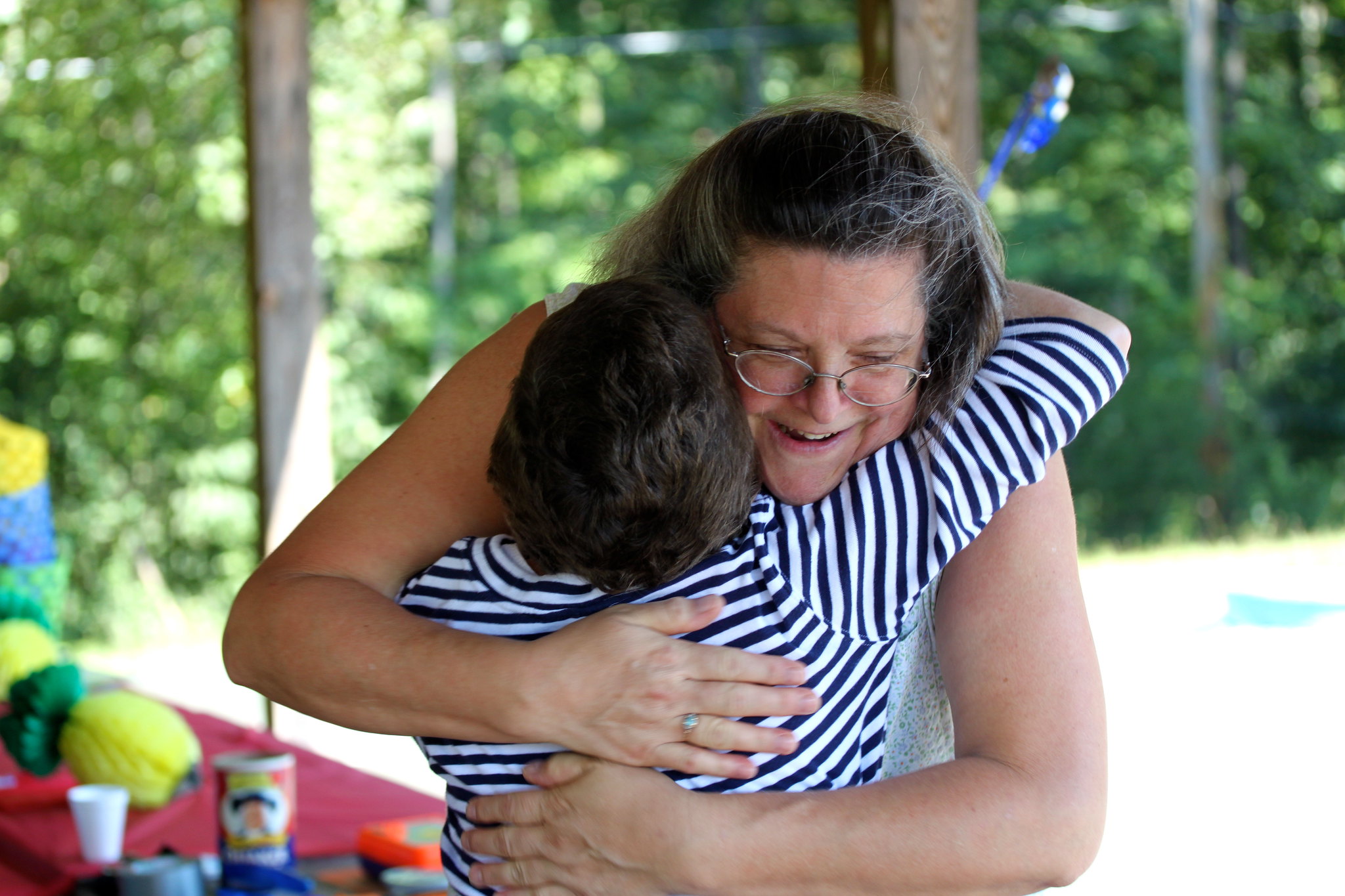 A woman with brown hair hugging a young child