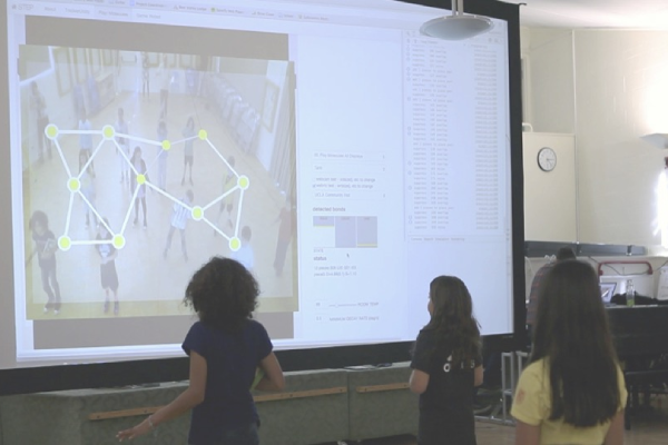 Young students act out the states of matter, in this case by moving closer together to create a solid sheet of ice that is shown by their positions on the screen. (Enyedy lab, Vanderbilt University)