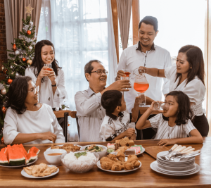 Pictured: A family of 7 is gathered around the table. Some are sipping from glasses while others are toasting to each other.