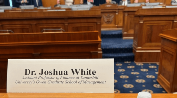 Pictured: White's perspective at the hearing, "Reforming the Proxy Process to Safeguard Investor Interests.”. His name card reads "Dr. Joshua White, Assistant Professor of Finance at Vanderbilt University's Owen Graduate School of Management." The background of the photo shows the room where the hearing was located.