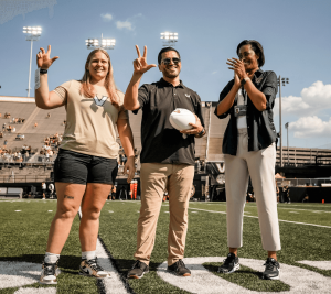 Pictured from Left to Right: Sarah Marvin, Mario Avila, and Candace Storey Lee. Marvin and Avila hold up the "VU" hand sign that is popular to show Vanderbilt pride. Lee is clapping.